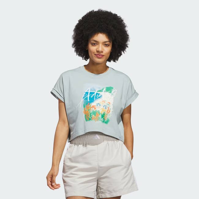 Person wearing a casual outfit with a graphic harvest apical and shorts, suitable for relaxed summertime shopping