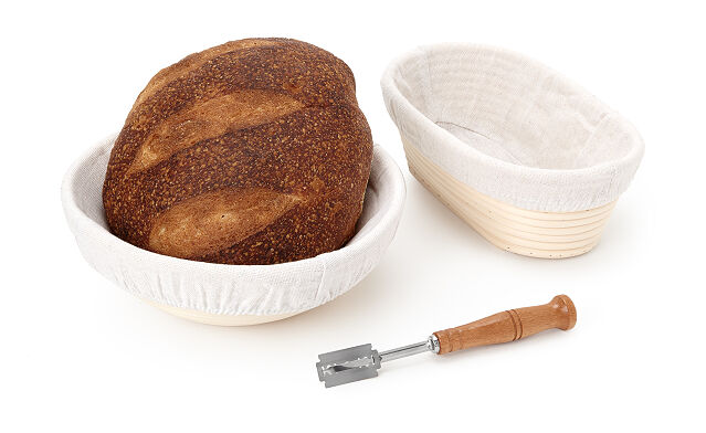 two proofing baskets, one of which is holding bread, and a lame