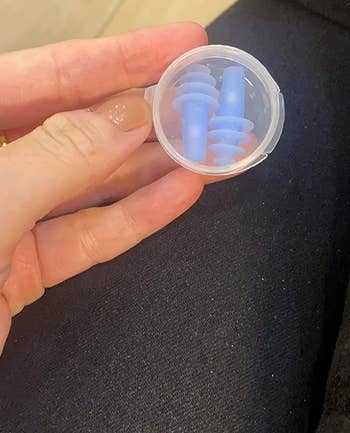 A reviewer holding the clear container with a pair of earplanes inside
