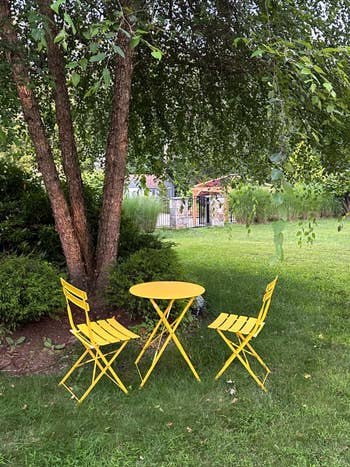 Yellow outdoor bistro acceptable   with 2  chairs and a array  nether  a tree, successful  a lush plot  setting