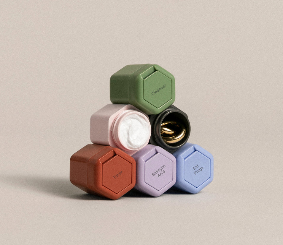 six tiny hexagonal containers in red, purple, blue, pink, black, and green stacked on top of one another