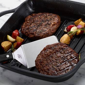 Two cooked burgers successful  a grill cookware  with roasted potatoes and herbs, showcasing a room  tool. Great for a buying  nonfiction  connected  cookware essentials