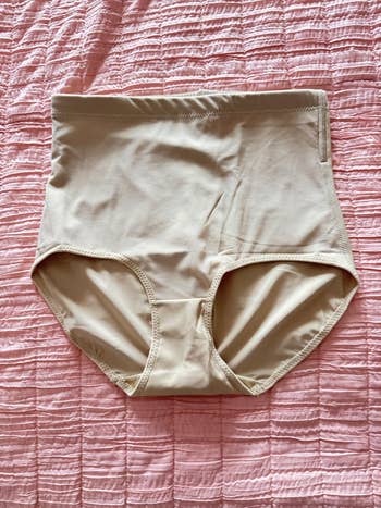 High-waisted beige shapewear briefs connected a textured surface