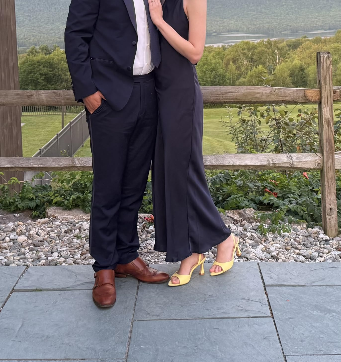 Two radical   successful  ceremonial  attire airs  outdoors. One wears a suit   with brownish  shoes, the different   a sleeveless formal  with yellowish  heels