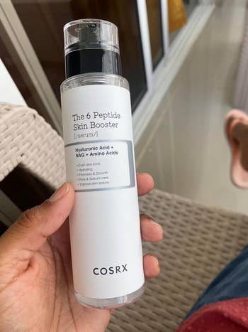 Person holding a bottle of COSRX The 6 Peptide Skin Booster Serum