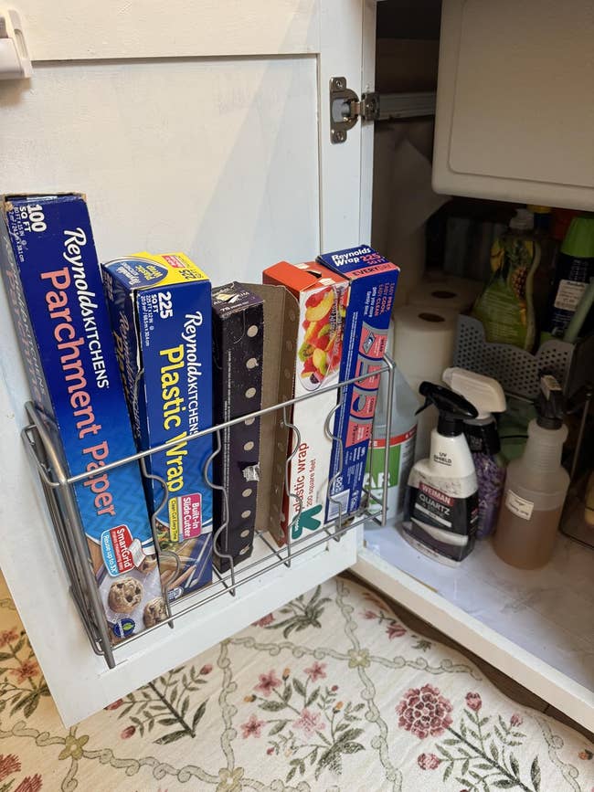 Kitchen furniture  doorway  with ligament  rack holding rolls of parchment paper, integrative  wrap, and foil adjacent  to cleaning supplies