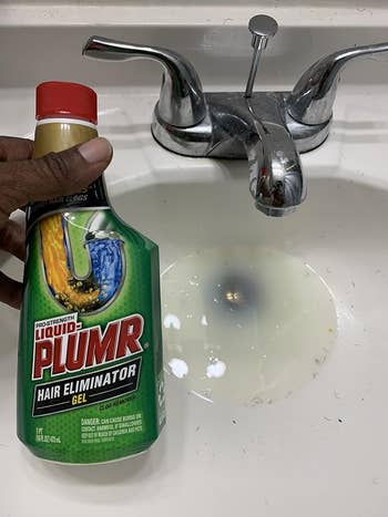 reviewer holding bottle of liquid plumr next to clogged drain
