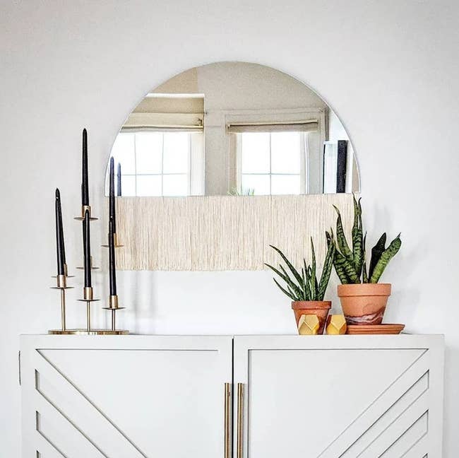 half mirror with ivory fringe hanging above a 