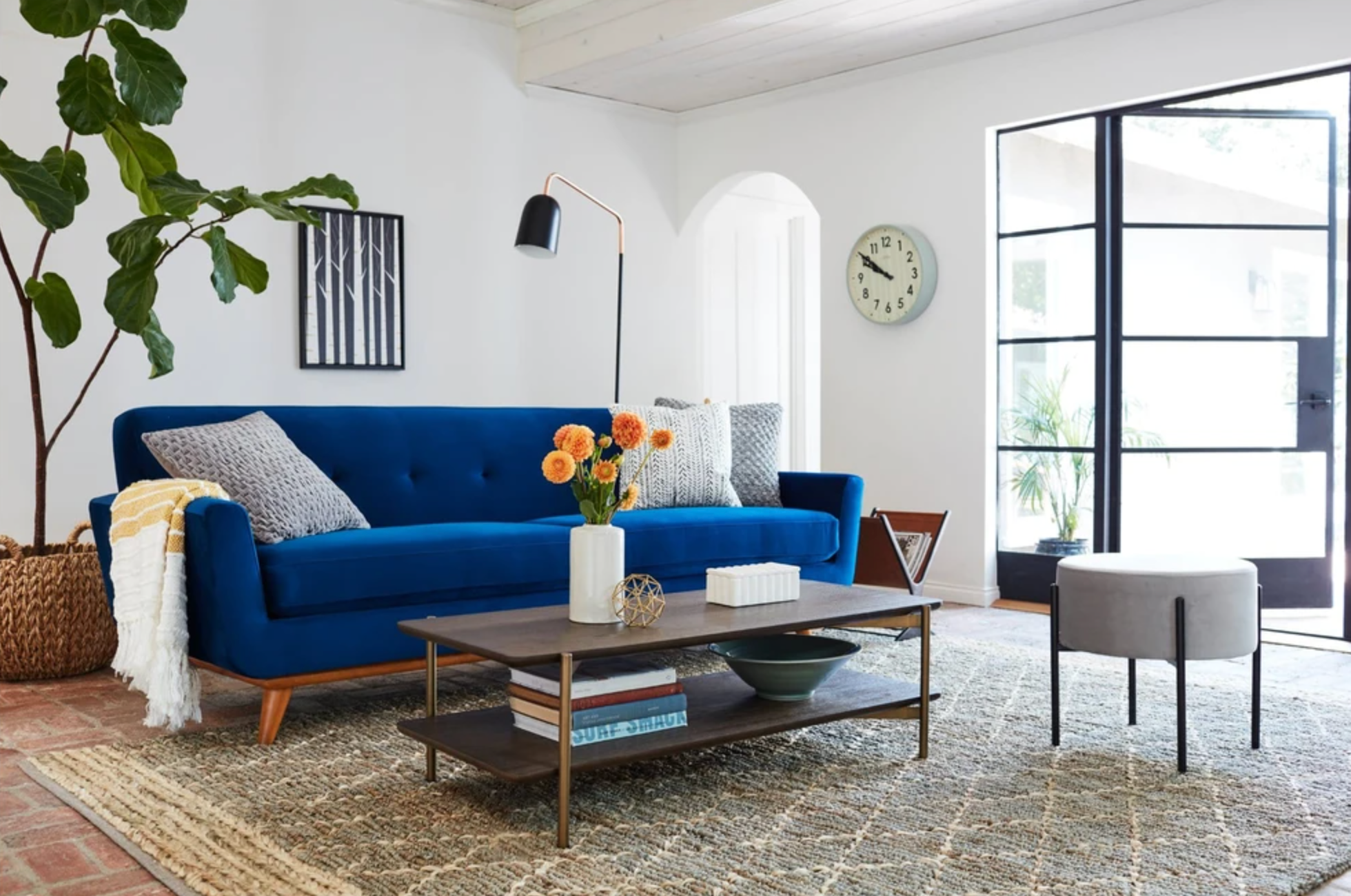 cobalt blue sofa with low, warm wood legs on an angle with two removable bottom cushions and a tufted back 