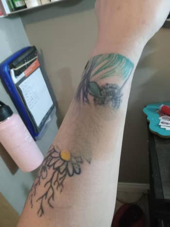 Floral tattoos connected  forearm beside pinkish  h2o  vessel  and clipboard connected  a desk