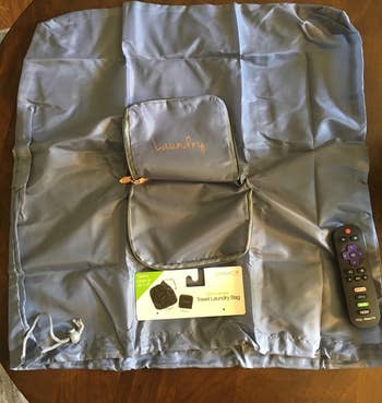 a reviewer photo of the same bag unfolded with thew same remote present for scale 