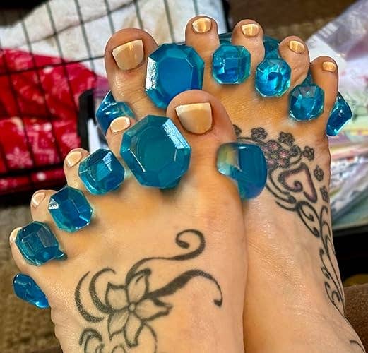 Feet with bluish gem-like toed separators, featuring intricate floral tattoos