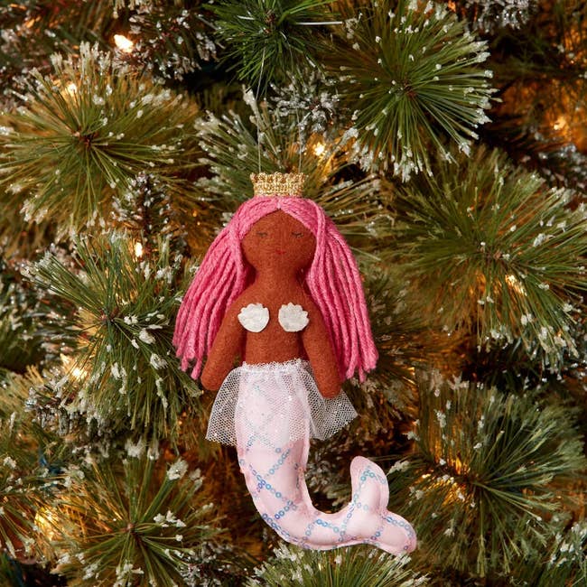 a felt mermaid with pink har, brown skin, and a pink tail