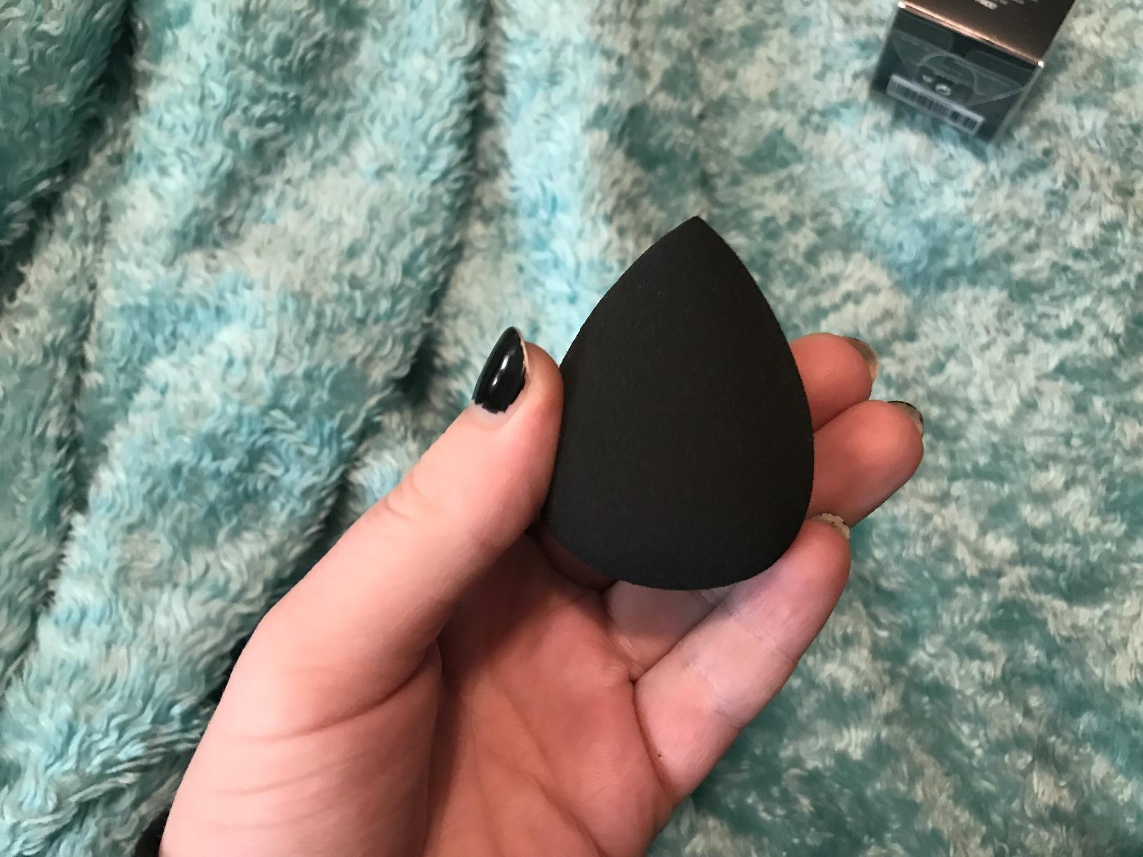 hand holding a black makeup sponge