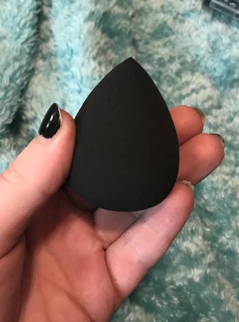 hand holding a black makeup sponge