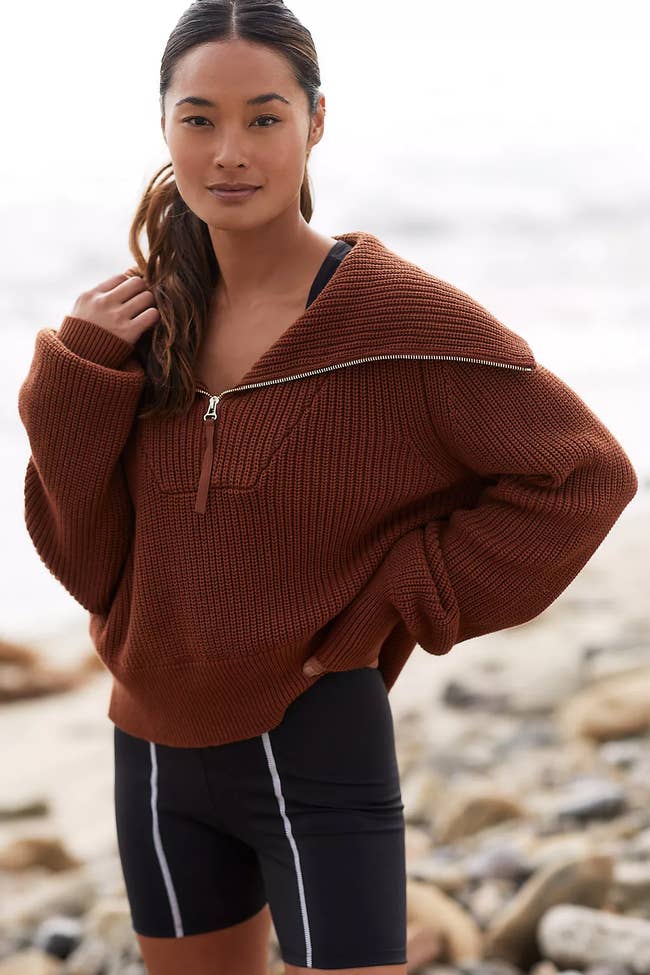 model in oversized sweater and shorts standing on a beach