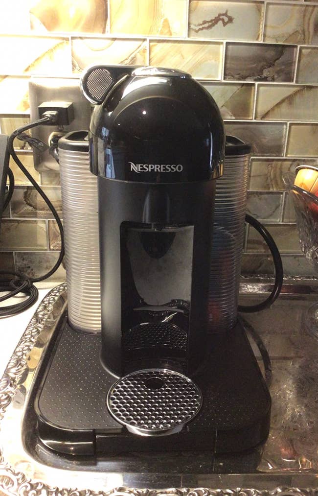 A black nespresso coffee maker perched on a reviewer's kitchen counter 