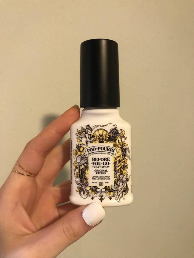 image of reviewer's hand holding up bottle of poo-pourri