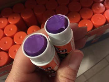 reviewer holding two purple glue sticks