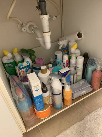 under bathroom sink with no storage and a jumble of products