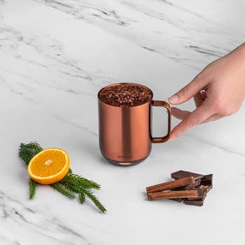 the copper mug next to a half an orange, chocolate, and cinnamon sticks