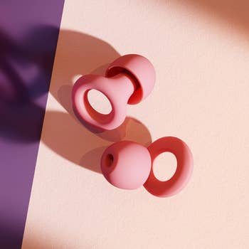 A set of small pink earplugs with loops on them 