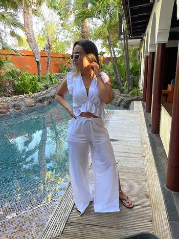 reviewer posing in white outfit by a pool