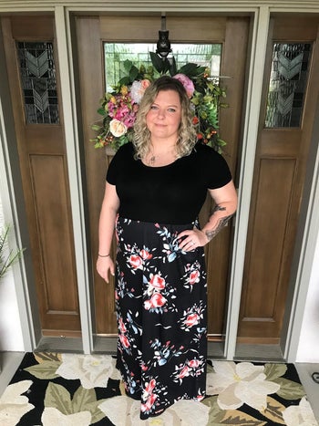 Lady in sad high and floral skirt standing in doorway with ornamental wreath