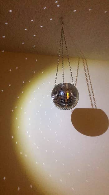 reviewer photo of the disco ball planter hanging from the ceiling and reflecting light on their wall