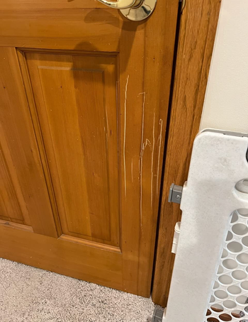 A reviewer's before photo with scratches on their wooden door
