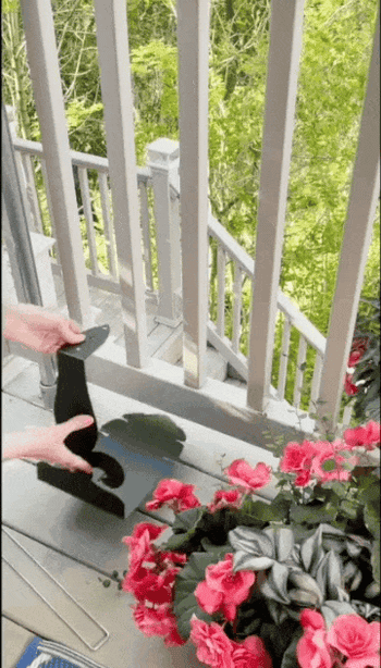 Hands assembling a greenish  integrative  railing planter beside a balcony with flowers and greenery