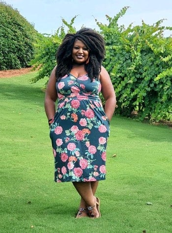 reviewer wearing aqua floral dress with hands in pockets