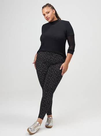 Person wearing a chic achromatic apical and patterned leggings, paired with metallic sneakers, posing confidently