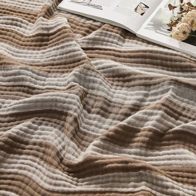 A cozy, wavy-patterned broad  is dispersed  retired  adjacent  to an unfastened  book, suggesting a comfy  speechmaking  spot