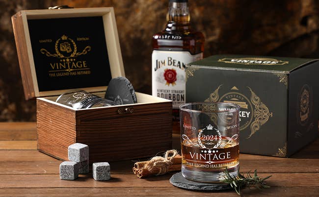 a wooden box behind a glass of whiskey and four stone cubes