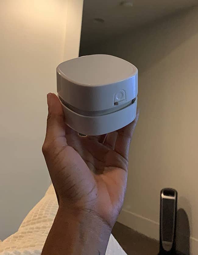 A reviewer holding the small, square, white vacuum
