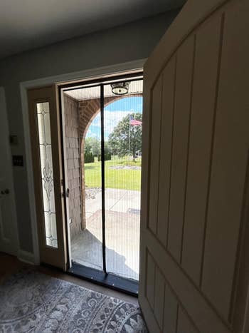 A door open with a screen door that's closed in the middle with magnets