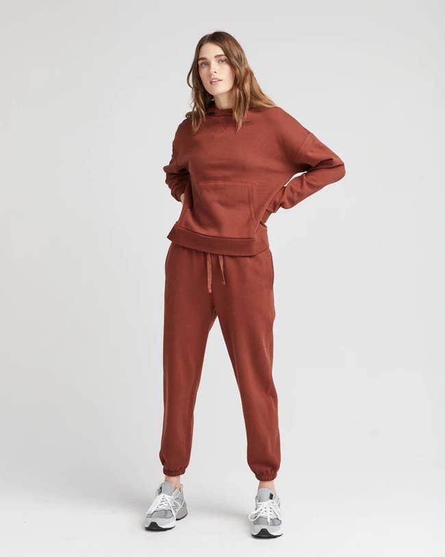 a model wearing a burnt red hoodie and sweatpants