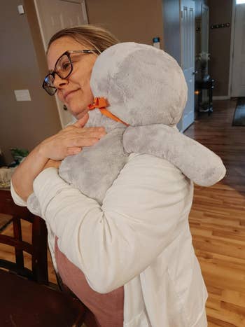 reviewer hugging the sloth plushie