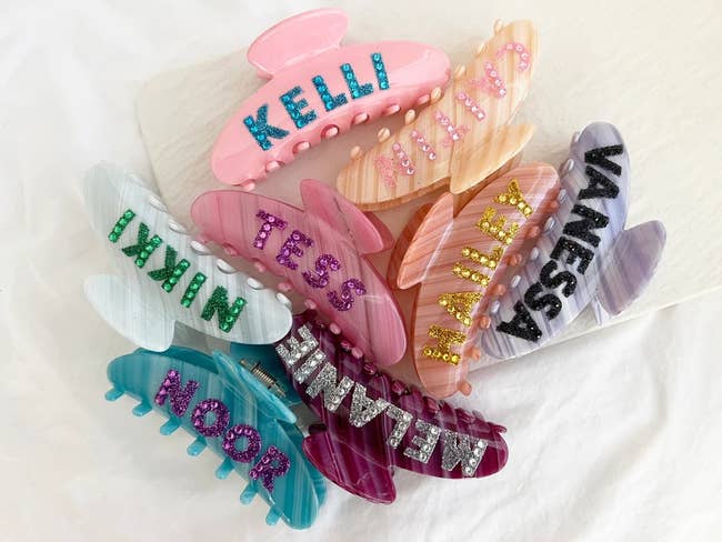 a pile of acrylic claw clips in different colors with different names on each one