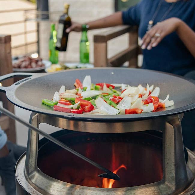 wok top on stand above solo stove with two people prepping food