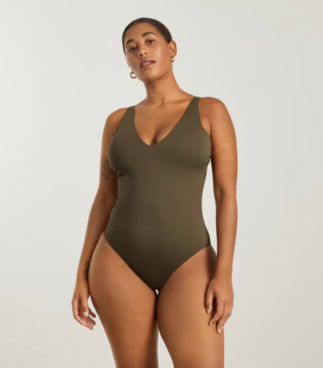 Model in a deep green v-neck one piece swimsuit 