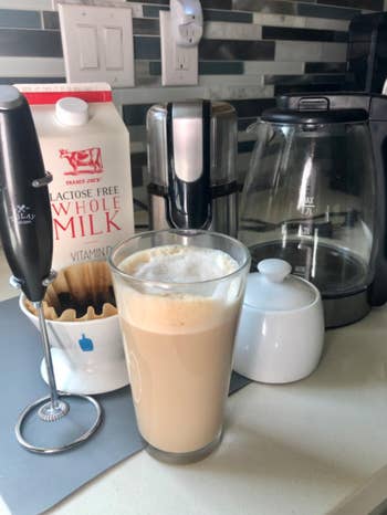the milk frother next to a cup of coffee 