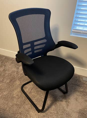 Reviewer image of black mesh chair on brown carpet and tan wall