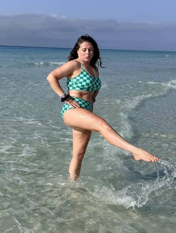Person successful a checkered swimsuit playfully kicks h2o astatine the beach