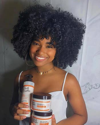 Person holding the shampoo and other curl products