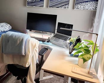 Home office setup with a desk, dual monitors, laptop on stand, desk lamp, and a plant
