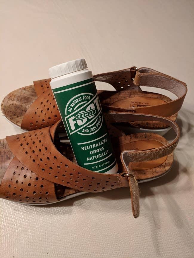 reviewer image of a bottle of the odor eliminator in a pair of brown sandals