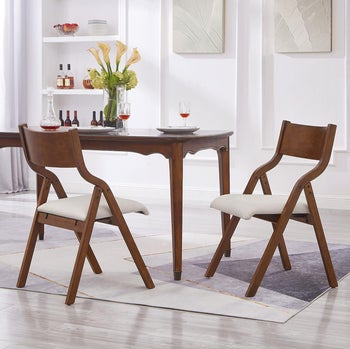 A contemporary dining set with a wooden table and two chairs with cushioned seats