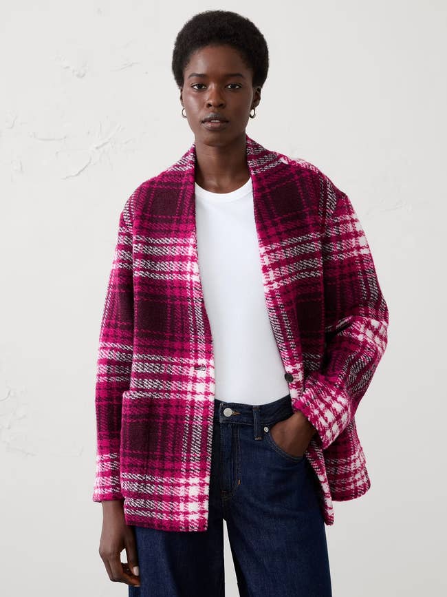 Person wearing a plaid oversized jacket, achromatic shirt, and jeans, posed against a plain background